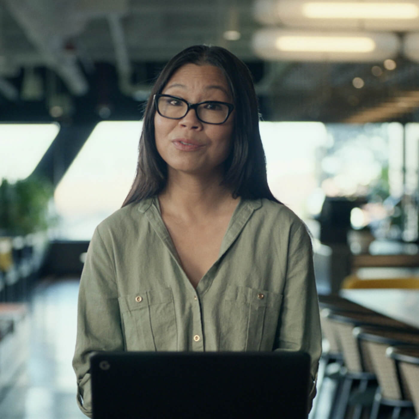 Image: a person with glasses sitting in front of a computer speaking.